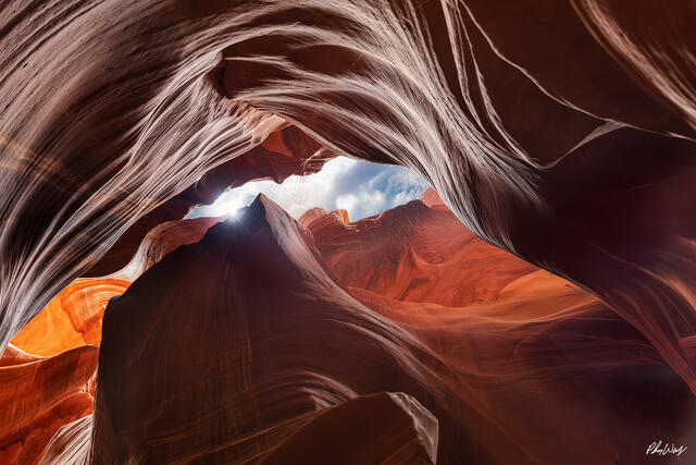 Sunlight streaming through Antelope Canyon illuminating smooth red sandstone walls in Arizona.