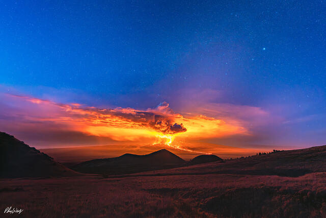 Mauna Loa eruption glowing at sunrise beneath a star filled sky on the Big Island of Hawaii.