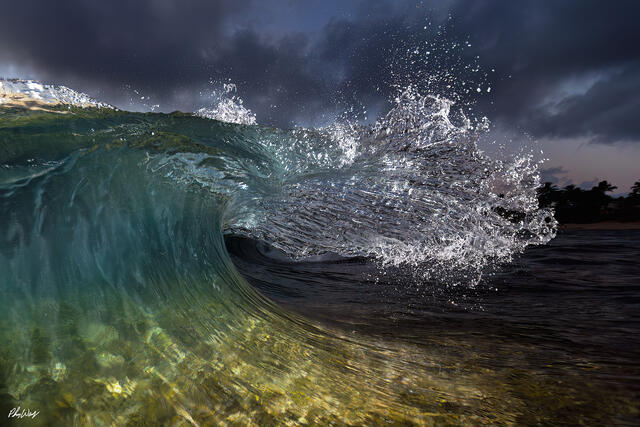Powerful ocean wave curling at night on the North Shore of Oahu with dramatic lighting.