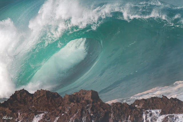 Powerful turquoise wave breaking against volcanic rock at Sharks Cove on Oahu Hawaii.