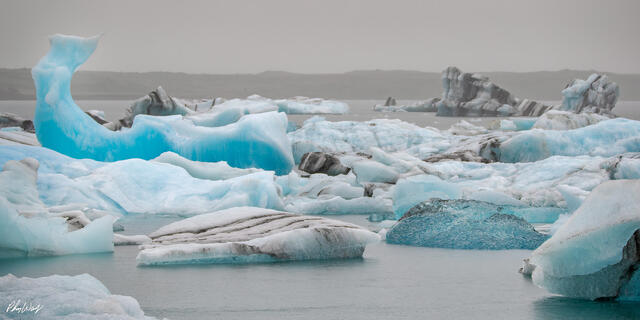 Floating blue icebergs drifting across Jokulsarlon Glacier Lagoon in Iceland.