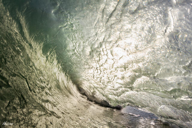Inside a hollow green ocean wave curling along the Malibu coastline in California.