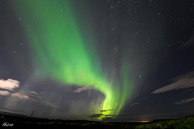 Green northern lights sweeping across a star filled night sky near Reykjavik Iceland.