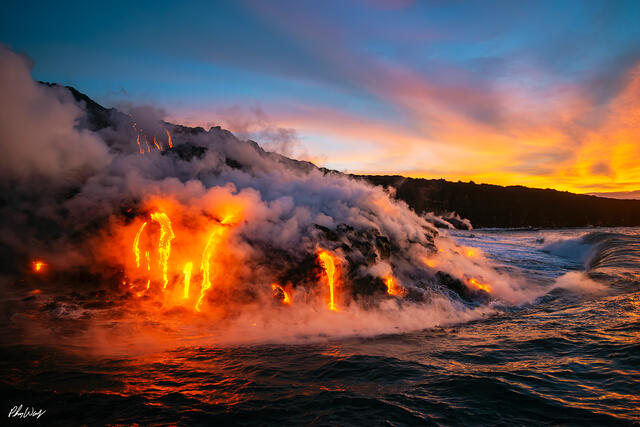 Molten lava flowing into the ocean at sunrise in Kalapana on the Big Island of Hawaii.
