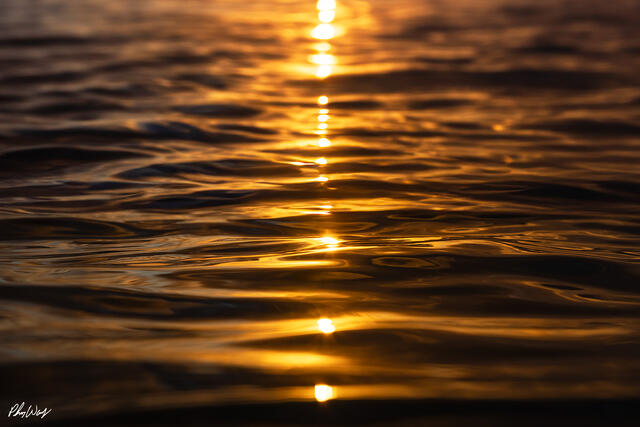 Golden sunset light reflecting across rippling ocean water in Kona on the Big Island of Hawaii.