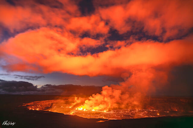 Glowing lava field at sunrise with red clouds and rising steam at Kilauea volcano.