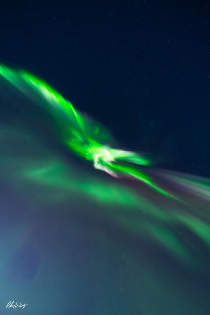 Green aurora borealis flowing across a dark star filled sky over Reykjavik, Iceland.