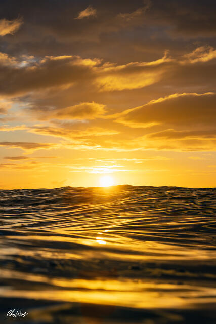 Golden sunset reflecting across ocean waves at Sunset Beach on Oahu Hawaii.