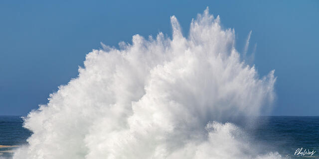 Exploding ocean wave sending a powerful plume of white water into the air against a blue sky at Haleiwa on Oahu.