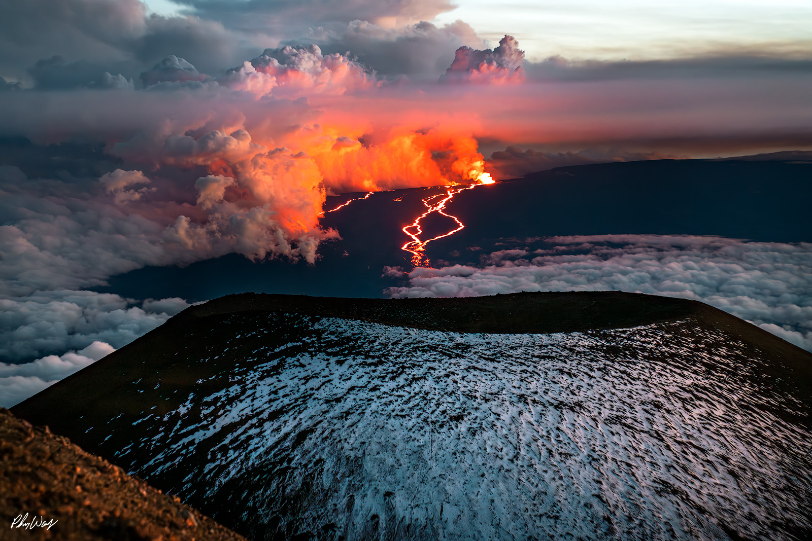 Mauna Kea to Mauna Loa Lava Snow covered Mauna Kea foreground with glowing Mauna Loa lava eruption and clouds on the Big Island.