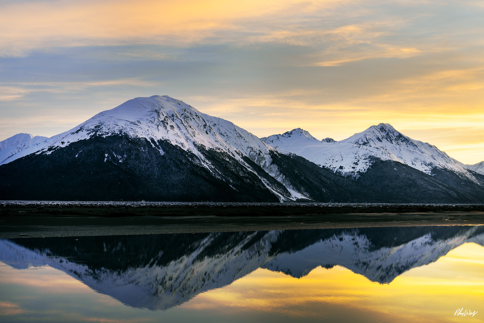Kenai Reflection Snow covered mountains reflected in calm water beneath a soft golden sky in Kenai Alaska.