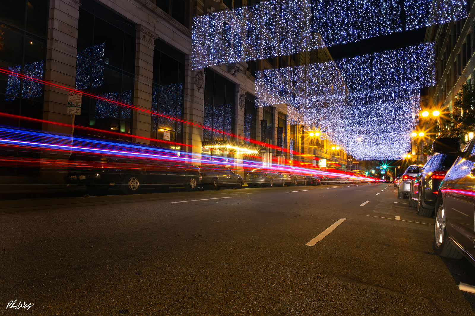 Downtown Exposure Night photograph of downtown Los Angeles street with long exposure light trails and illuminated overhead decorations.