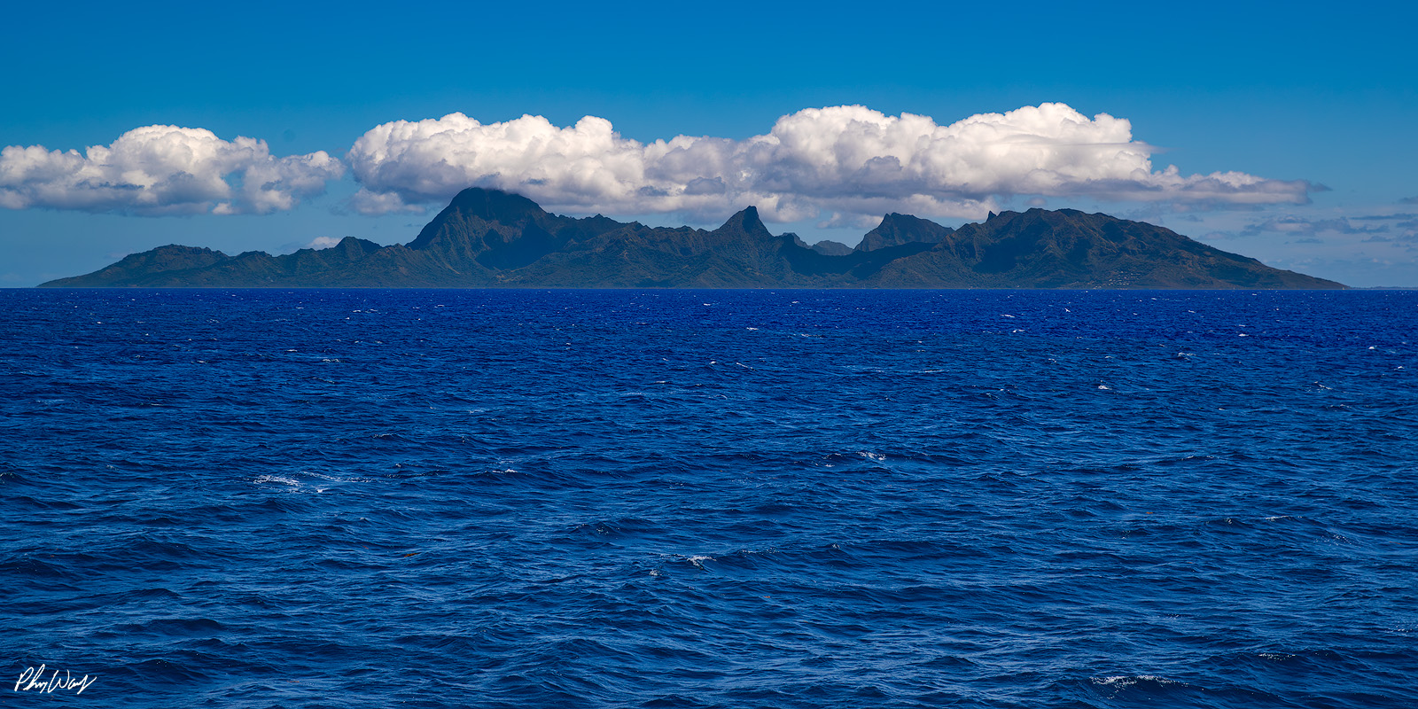 Mo'orea Island Distant view of Mo'orea Island with volcanic mountains rising above the ocean in Tahiti.