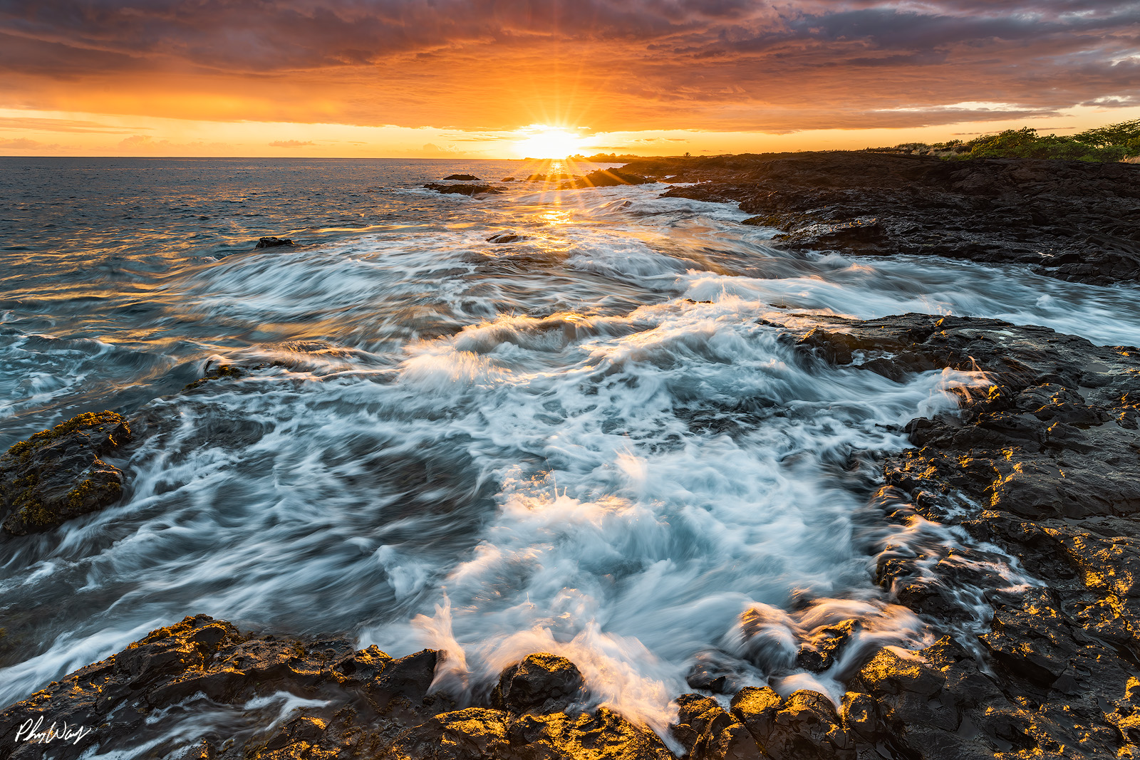 Velvet Blur Ocean waves flowing over volcanic rock at sunset with golden light reflecting on the water