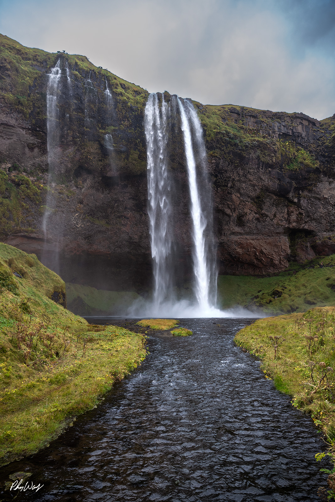 Water Fall Path River leading to a tall waterfall surrounded by mossy cliffs at Gljufrabui in Iceland.